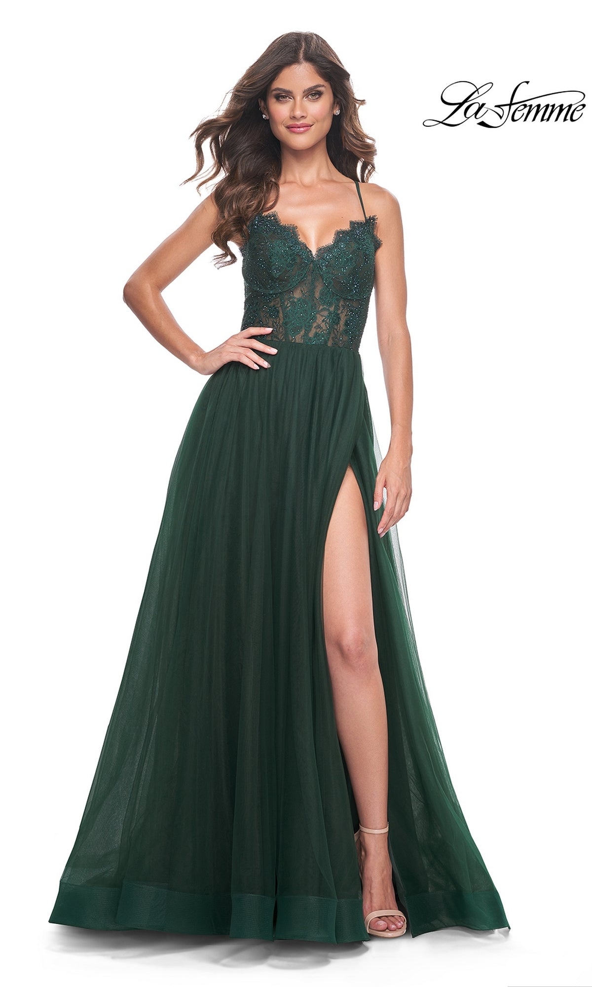Woman in the La Femme Lace-Bodice Long A-Line Prom Dress 32306, featuring a sleeveless dark green design with a sheer lace bodice and high leg slit, poses confidently with one hand on her hip.